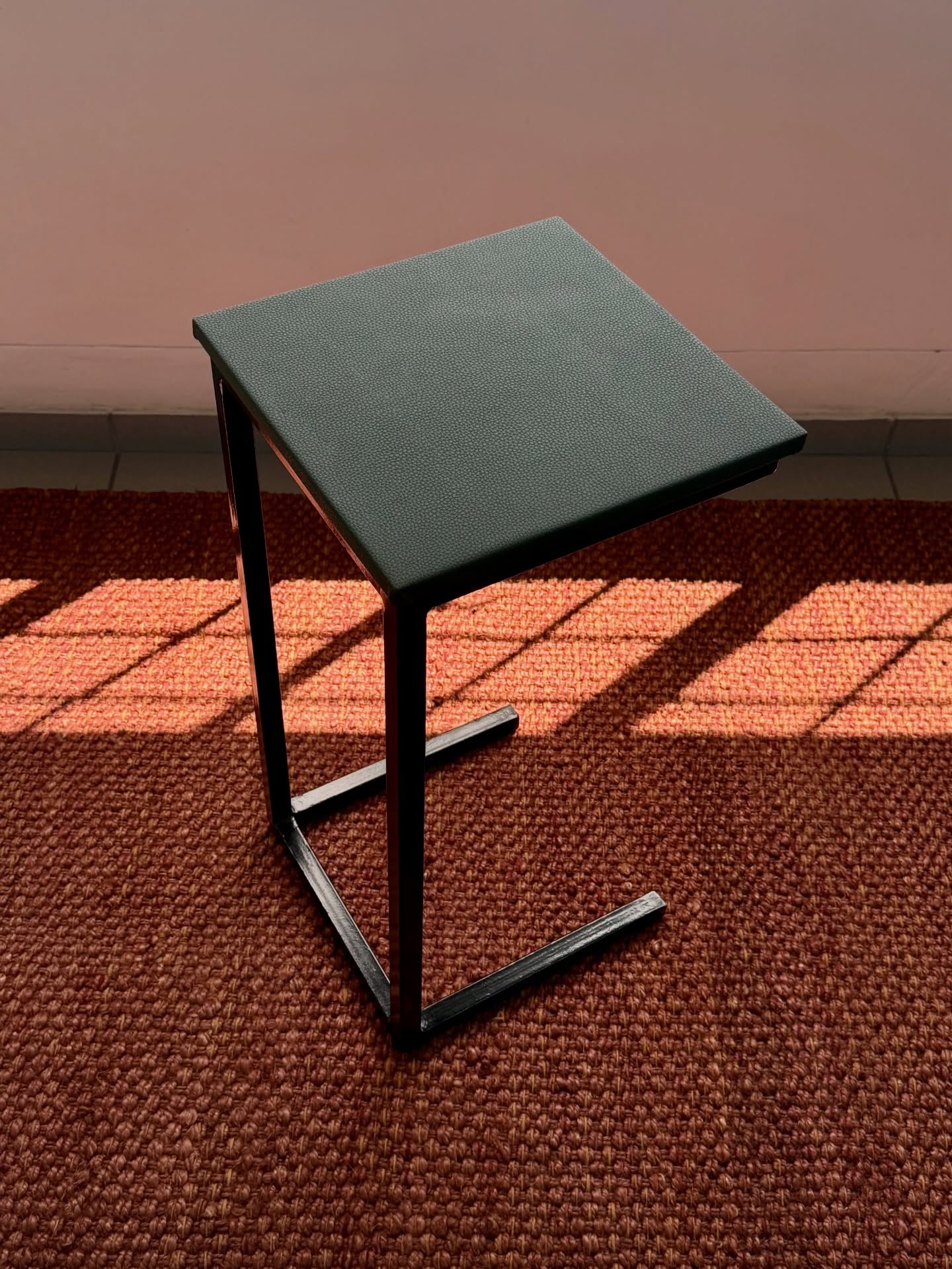 C-shaped side table with green shagreen-textured top on a black steel cantilever frame