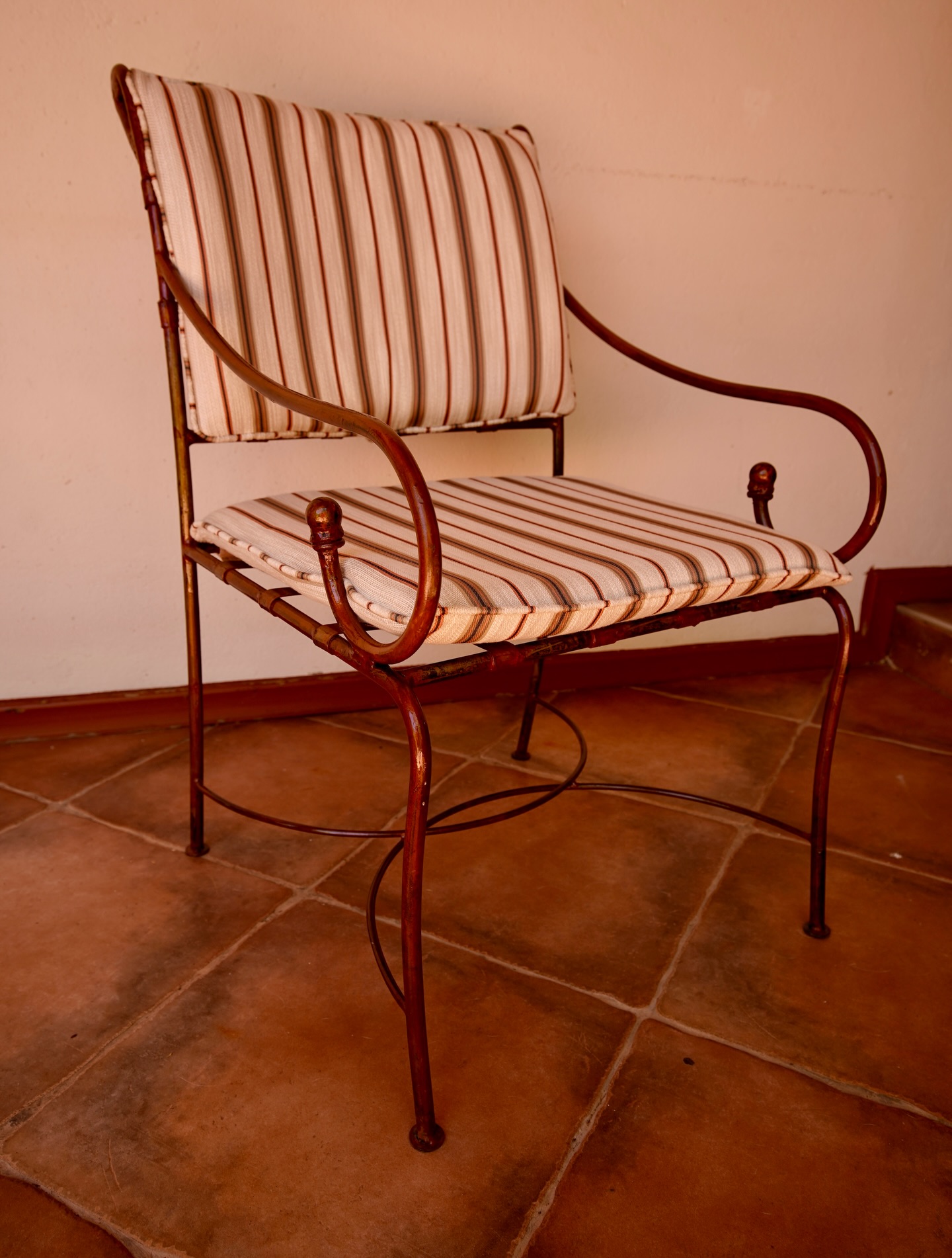 Restored vintage iron armchair with copper-rust frame and striped upholstered seat and back