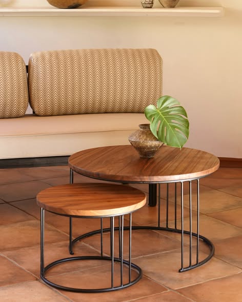 Pair of round nesting coffee tables with solid wood tops and black wire frame bases