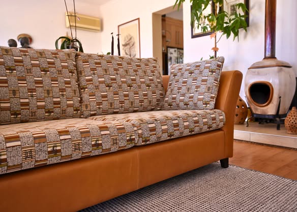 Tan leather three-seater sofa with geometric pattern back cushions