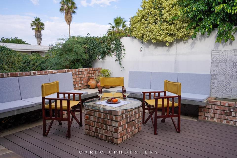 Carlo Upholstery outdoor patio installation — built-in bench seating and director's chairs around a brick fire pit